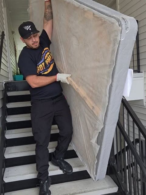 Got Junk NC crew member carrying a mattress down apartment stairs in Greenville, NC